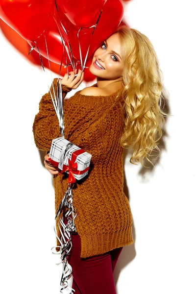 美丽快乐甜蜜微笑金发女人的女孩手里拿着她圣诞礼物盒和心的气球在休闲棕色时髦冬季毛衣衣服的肖像 — 图库照片