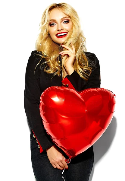 Porträtt av vackra glad söt leende blond kvinna tjej håller i hennes händer rött hjärta ballong i casual svart hipster kläder med röda läppar — Stockfoto