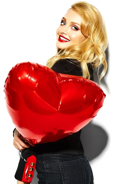 Portrait of beautiful happy sweet smiling blonde woman girl holding in her hands red heart balloon in casual black hipster clothes with red lips — Stock Photo, Image