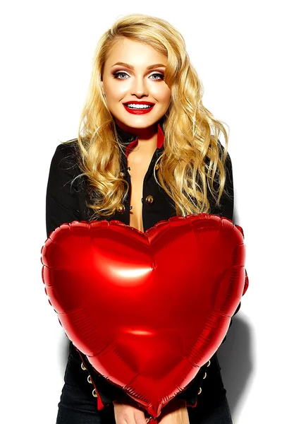 Portrait of beautiful happy sweet smiling blonde woman girl holding in her hands red heart balloon in casual black hipster clothes with red lips — Stock Photo, Image