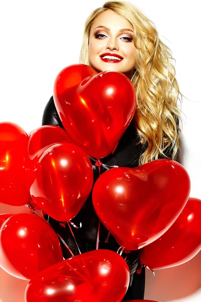Portrait of beautiful happy sweet smiling blonde woman girl holding in her hands red heart balloons in casual black hipster clothes — Stock Photo, Image