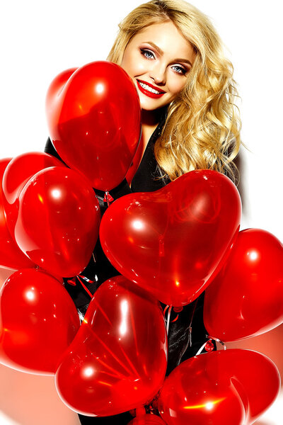 portrait of beautiful happy sweet smiling blonde woman girl holding in her hands red heart balloons in casual black hipster clothes