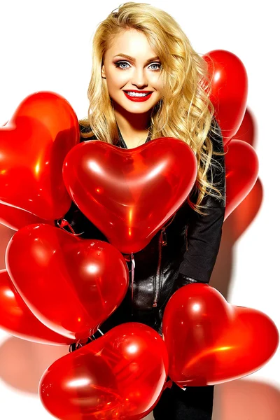 Portrait of beautiful happy sweet smiling blonde woman girl holding in her hands red heart balloons in casual black hipster clothes — Stock Photo, Image