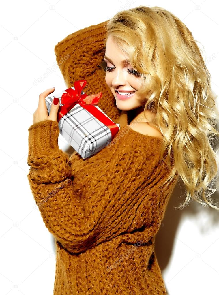 portrait of beautiful happy cute smiling blonde woman girl holding in her hands  Christmas gift box in casual brown  hipster winter sweater clothes