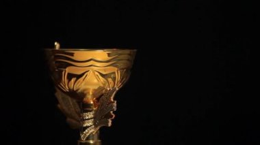 Koyu arkaplanda dönen altın kupa görüntüleri.