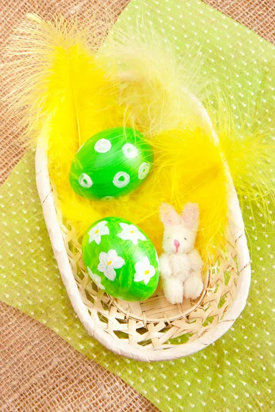 Uova di Pasqua in un cesto con piume gialle — Foto Stock
