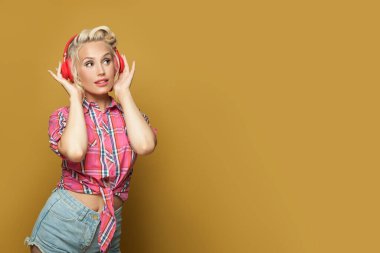 Parlak sarı pankartta kulaklıklı çekici bir kadın.