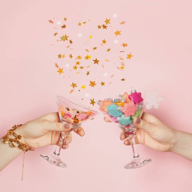 Noel arkaplanı. Şarap kadehi, Xmas dekorasyonu ve pastel pembe kartın üzerine düşen altın rengi konfeti yıldızlarıyla en düşük kompozisyon.