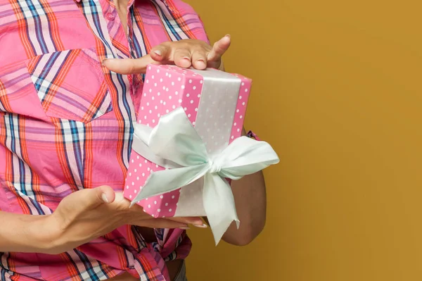 Pembe benekli hediye kutusu beyaz ipek kurdeleli retro model kadın elleri sarı arka planda