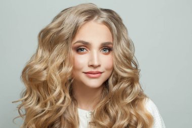 Gülümseyen, doğal makyajlı, kıvırcık saçlı, sarışın kadın.