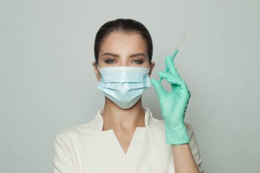 Beyaz arka planda elinde şırınga tutan profesyonel üniformalı bir doktor portresi. Tıp, kozmetoloji ve aşı kavramı