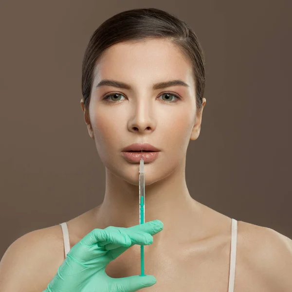 Lip augmentation and cosmetology injection. Nice woman with syringe near lips