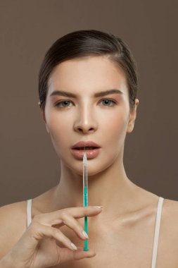 Kadın yüzü ve şırınga. Dudak büyütme kavramı
