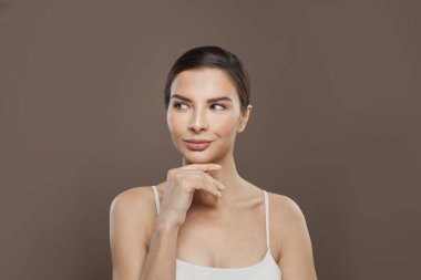 Kahverengi arka plan portresi üzerinde parlak tenli neşeli bir kadın.