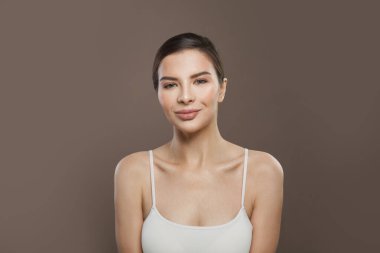 Kahverengi arka planda açık tenli mutlu genç bir kadın.