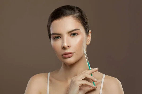 Perfect woman face with syringe injection on brown background. Cosmetology and aesthetic surgery concept