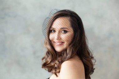 Gri kaplama arka planda siyah peçeli zarif retro kadın.