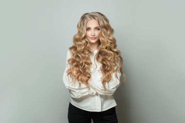 Sarışın kız öğrenci gülümsüyor ve beyaz arka planda duruyor.