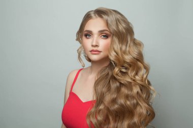 Beyaz arka planda uzun, kusursuz saçları olan güzel, sarışın bir kadın.