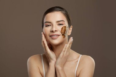 Kahverengi arka planda derisi fırçalanmış, gülümseyen bir spa kadını. Yüz bakımı, vücut bakımı ve cilt bakımı kavramı