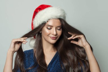 Beyaz arka planda Noel Baba şapkalı güzel esmer kadın, Noel portresi.