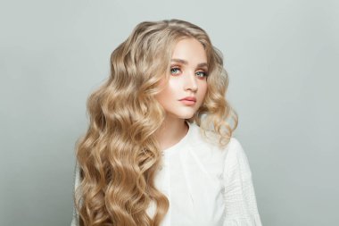 Beyaz arka planda sağlıklı sarı kıvırcık saçlı hoş bir kadın.