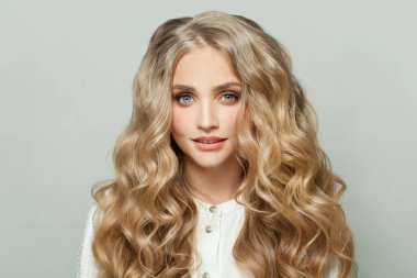 Beyaz arka planda sağlıklı sarı kıvırcık saçlı güzel bir kadın.