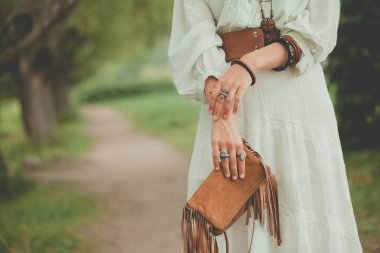 Dışarıdaki kadında şık kadın aksesuarları. Mücevher yüzükleri, tahta bilezik, süet kadın çantası.