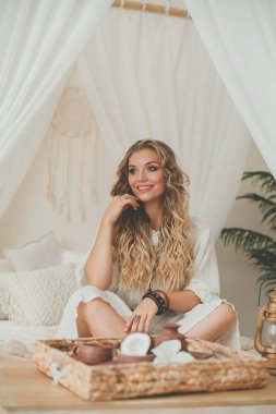 Sarışın, çekici genç bir kadın. Tropik bir otelde otel odasında eğleniyor.