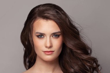 Kıvırcık kahverengi saçlı güzel bir kadın yüzü.