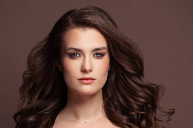 Kahverengi kıvırcık saçlı, esmer, sağlıklı bir kadın.