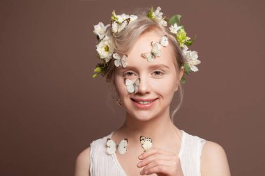 Kahverengi arka planda beyaz bahar çiçekleriyle gülümseyen mutlu kadın.