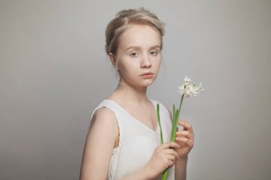 Beyaz arka planda sarı saçlı ve beyaz çiçekli hoş bir genç kadının portresi.