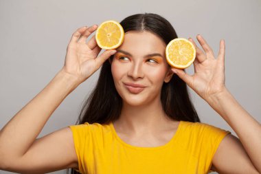 Temiz tenli, düz saçlı, beyaz arka planda limon meyvesi tutan mutlu ve sağlıklı bir kadın. Diyet, cilt bakımı ve yüz bakımı kavramı