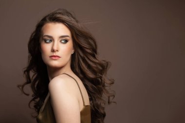 Çekici bir genç kadın. Kahverengi arka planda uzun, kahverengi saç stili.