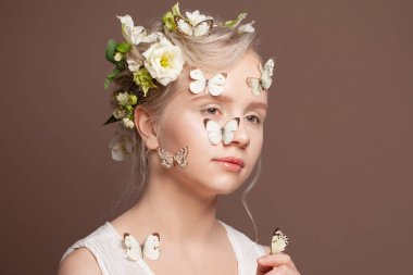 Beyaz bahar çiçekleri ve kahverengi arka planda kelebekleri olan çekici genç bir kadın.