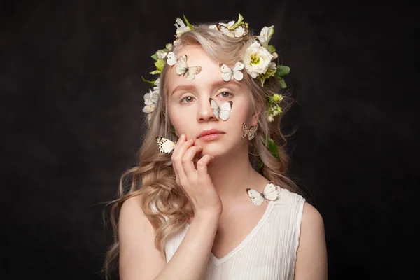 黒を背景に白い春の花と肌に蝶を持つ美しい若い女性 — ストック写真
