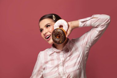 Çekici bir kadın elinde donut, kırmızı arka planda eğleniyor, diyet yapıyor ve kilo veriyor.