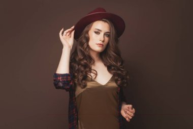 Fötr şapka takan kıvırcık saçlı melez genç kadın.