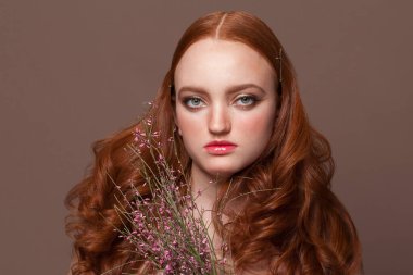 Mükemmel bir kızıl saçlının vesikalığı. Kızıl saçlı, kızıl saçlı, elinde çiçek tutan bir kadın.