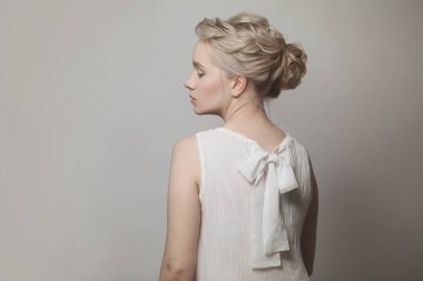 Gri pankartta beyaz elbise giyen, yeni moda saç stili olan zarif genç kadın modelin güzel profili