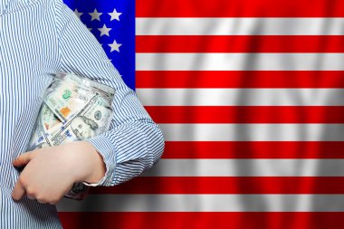 Amerikan bayrağı ve Amerikan doları. Rüzgarda dalgalanan Amerikan bayrağı ve ellerinde 100 dolarlık banknotlar.
