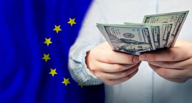 Avrupa Birliği bayraklarında dolar banknotları olan eller, borsada küresel ticaret kavramı, dünya para birimi için düşen ve yükselen fiyatlar