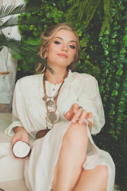 Tropikal tatil köyünde hindistan cevizi tutan güzel bir kadın.