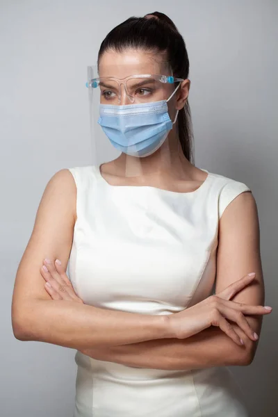 Female medical doctor wearing face shield and medical mask on white background. Portrait of female medical doctor wearing face shield for protect coronavirus with arms cross on white background
