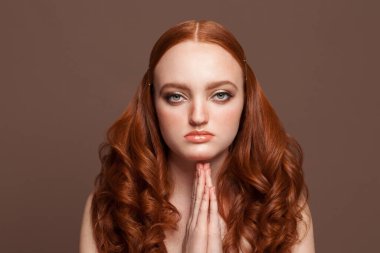 Güzel kızıl saçlı kadın ellerini yüzünün yakınında tutuyor.
