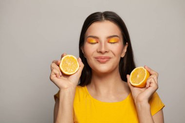 Neşeli esmer kadın beyaz arka planda sarı limon meyvelerinin tadını çıkarıyor.