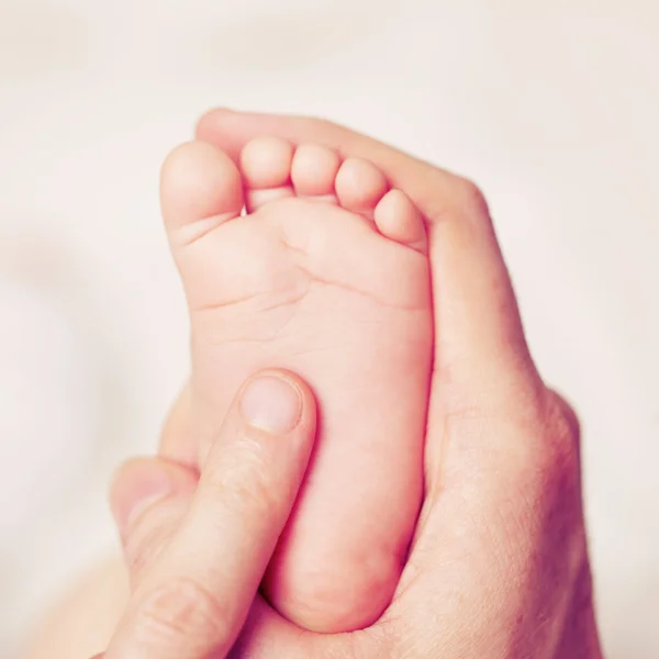 Male hand with baby feet — Stock Photo, Image