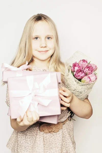 Girl holding a gift and flowers for his mother — Stock Photo, Image