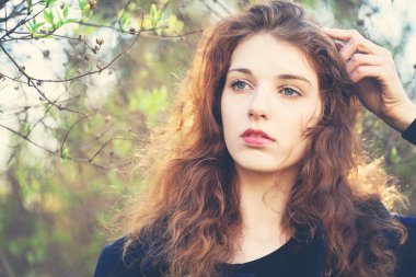 Açık havada, güneş ışığı kırmızı kıvırcık saçlı sevimli kız